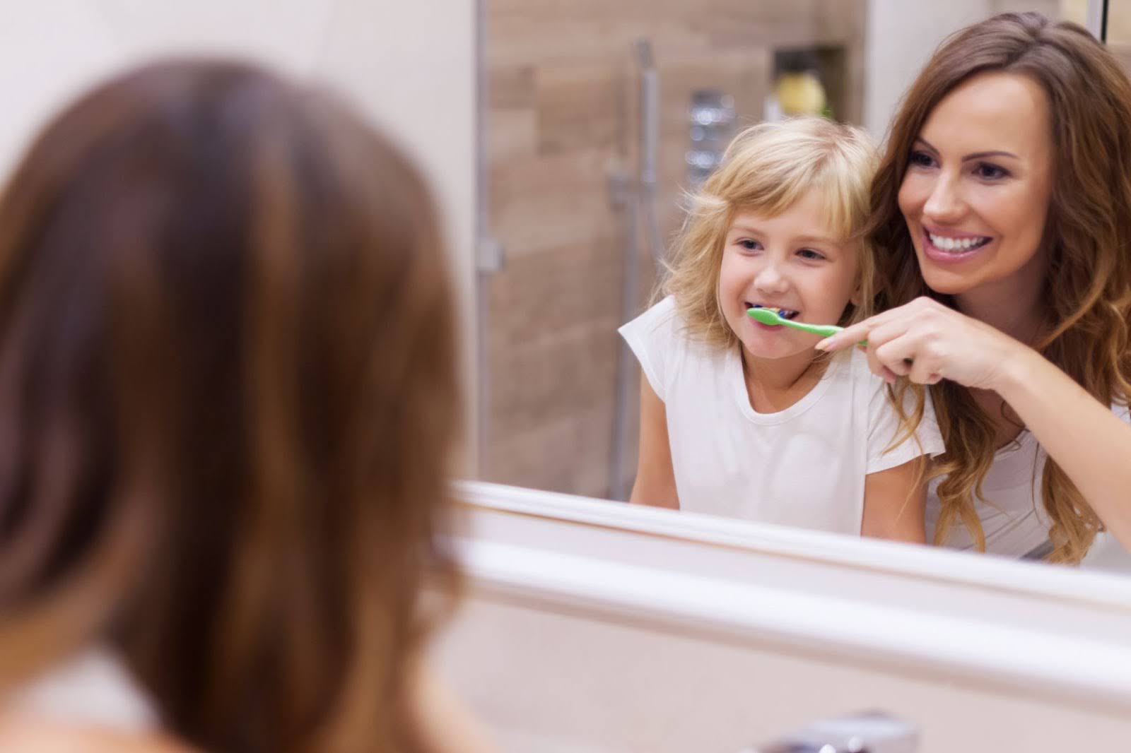 Mom and daughter brushing teeth at home.